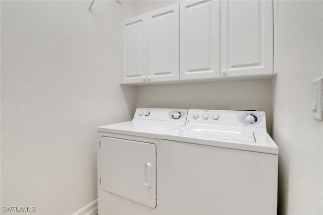 clothes washing area with independent washer and dryer and cabinet space
