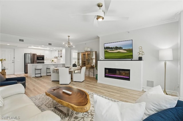 2728 Tiburon Blvd E Unit A104, Naples, FL 34109 - living room with ornamental molding, light wood-style floors, a chandelier, a glass covered fireplace, and ceiling fan
