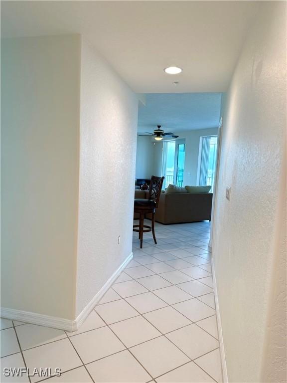 8751 Estero Blvd W Unit 304, Bonita Springs, FL 33931 - hallway with light tile patterned floors, baseboards, and a textured wall