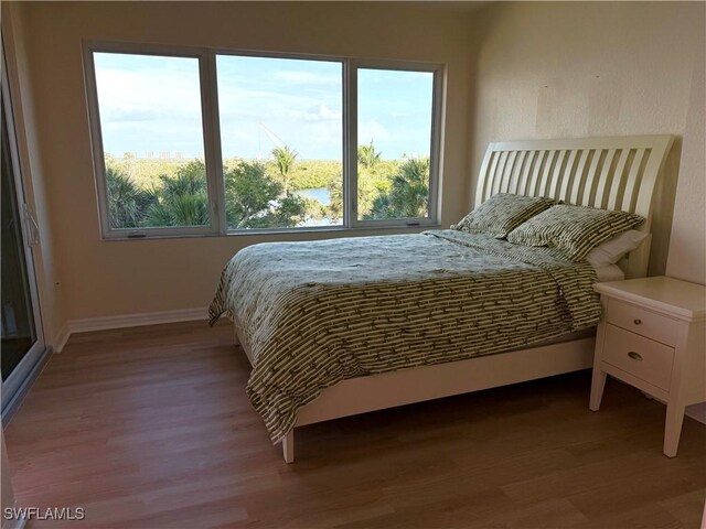 8751 Estero Blvd W Unit 304, Bonita Springs, FL 33931 - bedroom featuring wood finished floors, multiple windows, and baseboards