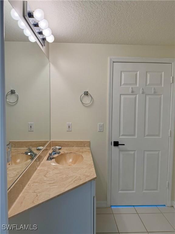 8751 Estero Blvd W Unit 304, Bonita Springs, FL 33931 - bathroom featuring vanity, tile patterned flooring, a textured ceiling, and baseboards