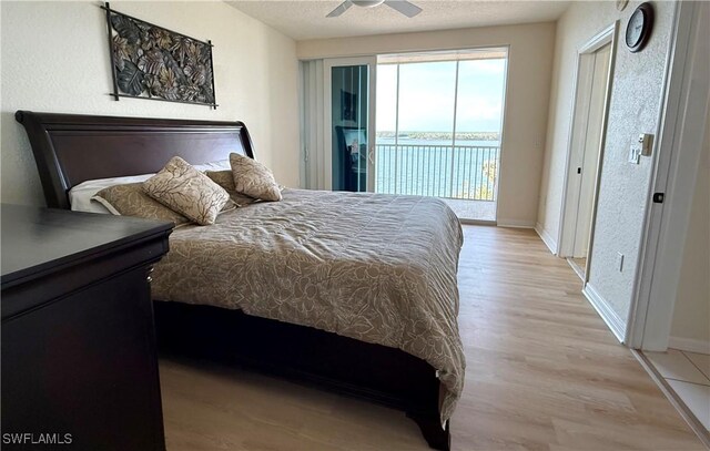 8751 Estero Blvd W Unit 304, Bonita Springs, FL 33931 - bedroom with access to exterior, light wood-type flooring, baseboards, ceiling fan, and a textured ceiling