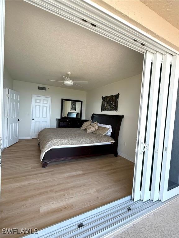 8751 Estero Blvd W Unit 304, Bonita Springs, FL 33931 - bedroom with light wood finished floors, baseboards, a textured ceiling, and ceiling fan