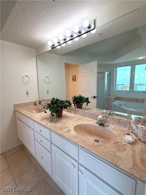 8751 Estero Blvd W Unit 304, Bonita Springs, FL 33931 - full bathroom with a stall shower, double vanity, a textured ceiling, tile patterned floors, and a bath
