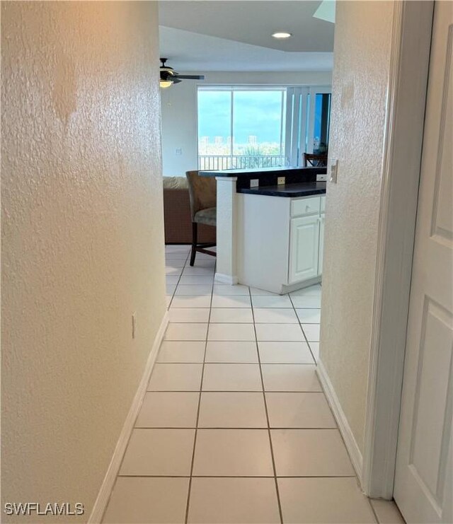 8751 Estero Blvd W Unit 304, Bonita Springs, FL 33931 - corridor featuring a textured wall, light tile patterned flooring, and baseboards