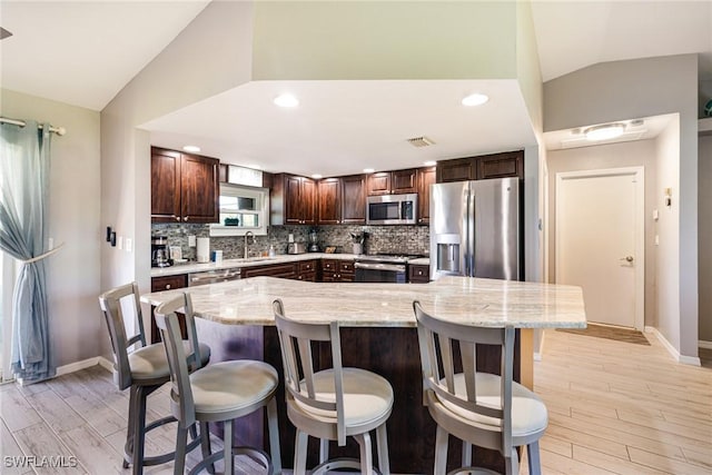 305 SW 8th St, Cape Coral, FL 33991 - kitchen with appliances with stainless steel finishes, lofted ceiling, a sink, tasteful backsplash, and dark brown cabinetry