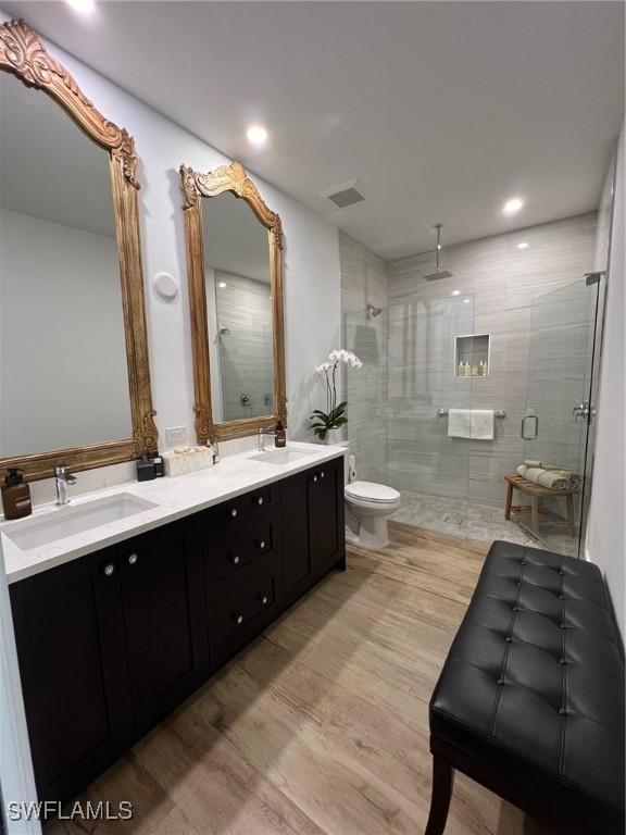 548 5th Ave, Marco Island, FL 34145 - bathroom with a shower stall, toilet, wood finished floors, double vanity, and recessed lighting