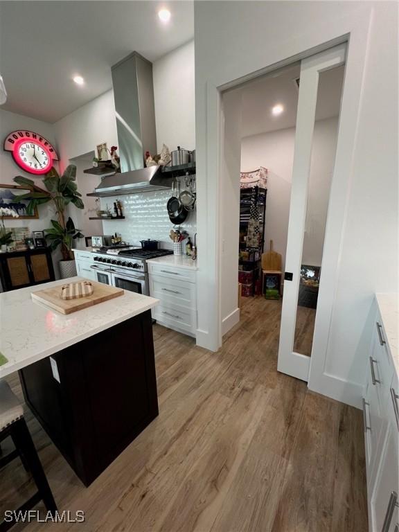 548 5th Ave, Marco Island, FL 34145 - kitchen featuring double oven range, wall chimney range hood, light wood-style flooring, light stone countertops, and recessed lighting