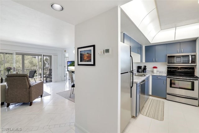 129 S Collier Blvd Unit B-206, Marco Island, FL 34145 - kitchen with stainless steel appliances, light tile patterned floors, blue cabinetry, open floor plan, and light stone countertops