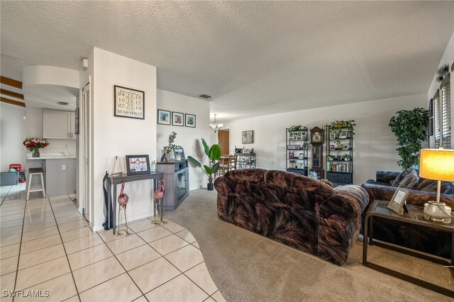 132 SW 34th Ln, Cape Coral, FL 33914 - living room featuring light carpet, light tile patterned floors, a textured ceiling, and a chandelier