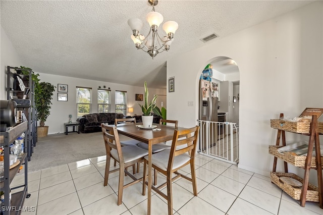 132 SW 34th Ln, Cape Coral, FL 33914 - dining space with arched walkways, a textured ceiling, light tile patterned flooring, a chandelier, and light colored carpet