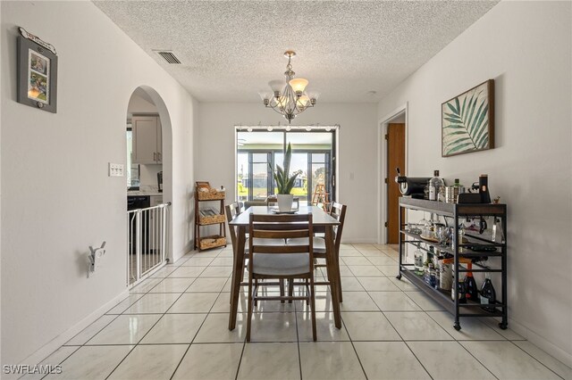 132 SW 34th Ln, Cape Coral, FL 33914 - dining room with a chandelier, arched walkways, a textured ceiling, light tile patterned floors, and baseboards