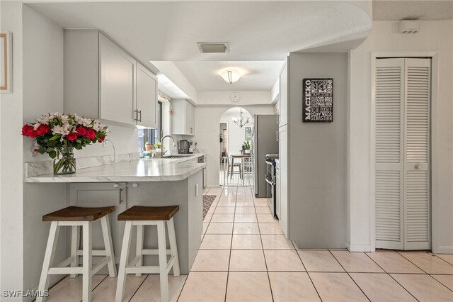 132 SW 34th Ln, Cape Coral, FL 33914 - kitchen featuring a sink, light countertops, a kitchen breakfast bar, light tile patterned floors, and a peninsula