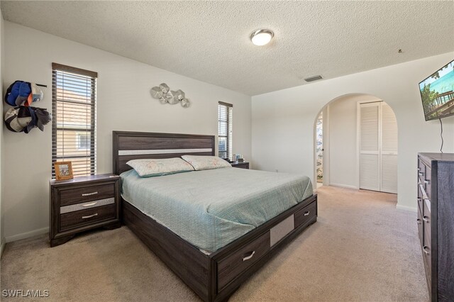 132 SW 34th Ln, Cape Coral, FL 33914 - bedroom with arched walkways, light colored carpet, a textured ceiling, and baseboards
