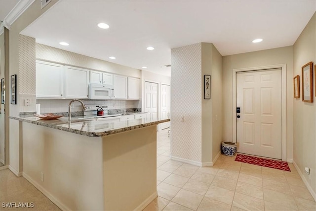 17040 Willowcrest Way Unit 209, Fort Myers, FL 33908 - kitchen with white appliances, baseboards, a peninsula, light stone counters, and white cabinets