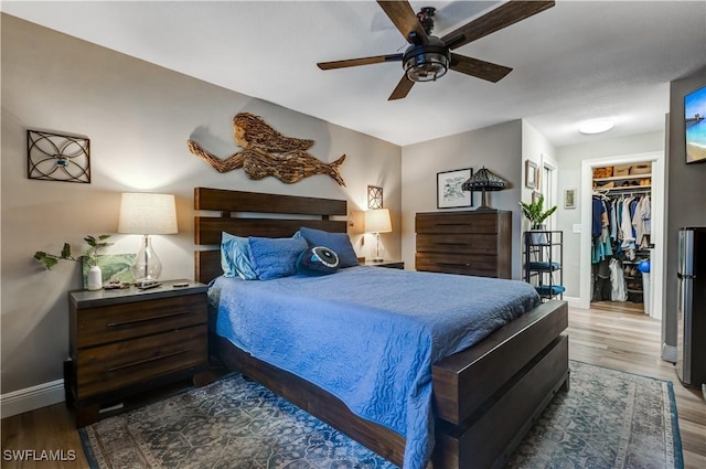 5692 Eichen Cir W, Fort Myers, FL 33919 - bedroom featuring baseboards, wood finished floors, a walk in closet, a ceiling fan, and a closet