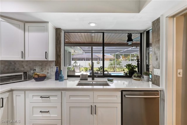 5692 Eichen Cir W, Fort Myers, FL 33919 - kitchen with stainless steel dishwasher, a sink, white cabinetry, light countertops, and tasteful backsplash