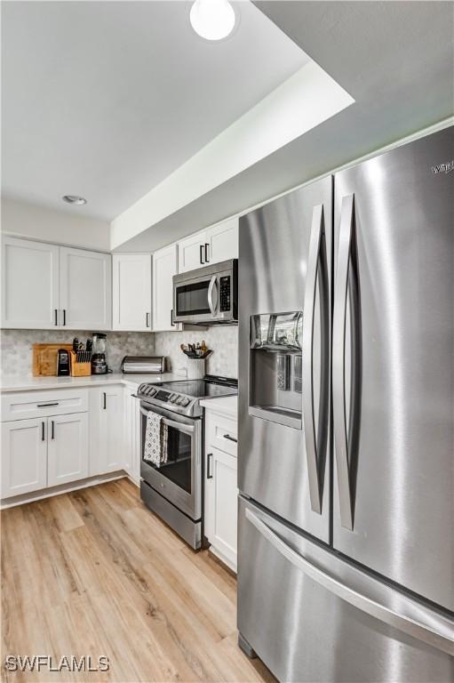 5692 Eichen Cir W, Fort Myers, FL 33919 - kitchen with stainless steel appliances, white cabinets, light countertops, and light wood-style flooring