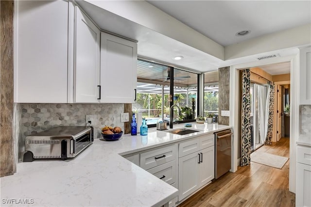 5692 Eichen Cir W, Fort Myers, FL 33919 - kitchen with stainless steel dishwasher, light wood-type flooring, white cabinetry, light stone counters, and recessed lighting