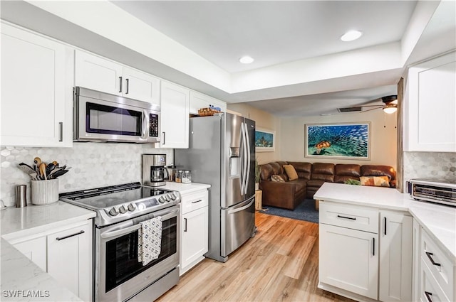 5692 Eichen Cir W, Fort Myers, FL 33919 - kitchen with stainless steel appliances, open floor plan, white cabinetry, light wood finished floors, and backsplash