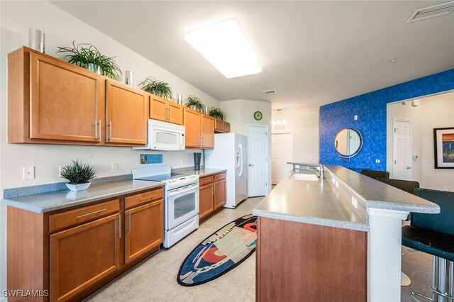 11741 Pasetto Ln Unit 403, Fort Myers, FL 33908 - kitchen featuring white appliances, a sink, a breakfast bar, a center island with sink, and light tile patterned floors