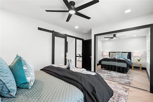 6212 Cocos Dr, Fort Myers, FL 33908 - bedroom with a barn door, light wood-style flooring, a ceiling fan, recessed lighting, and a closet