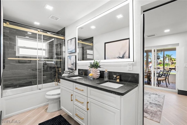 6212 Cocos Dr, Fort Myers, FL 33908 - bathroom with double vanity, shower / bath combination with glass door, toilet, wood finished floors, and recessed lighting