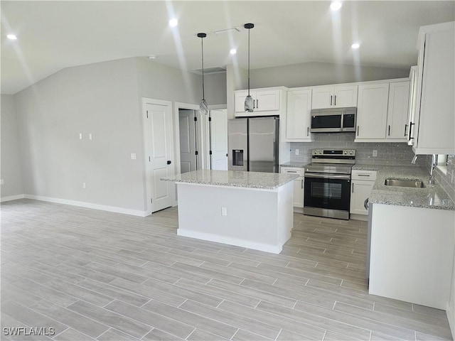 27584 Playa Del Rey Ln, Bonita Springs, FL 34135 - kitchen with stainless steel appliances, vaulted ceiling, decorative backsplash, a center island, and light wood-style floors