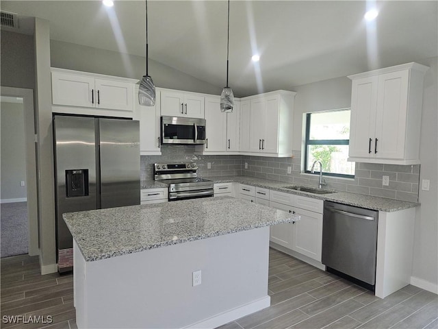 27584 Playa Del Rey Ln, Bonita Springs, FL 34135 - kitchen with stainless steel appliances, wood finish floors, a kitchen island, white cabinetry, and lofted ceiling