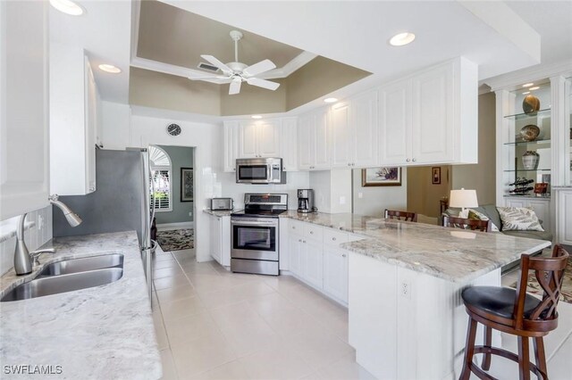 3774 Whidbey Way, Naples, FL 34119 - kitchen with stainless steel appliances, a peninsula, a sink, a kitchen breakfast bar, and a ceiling fan
