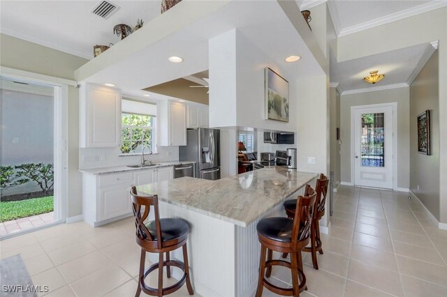 3774 Whidbey Way, Naples, FL 34119 - kitchen featuring appliances with stainless steel finishes, a sink, a kitchen bar, light stone counters, and ornamental molding