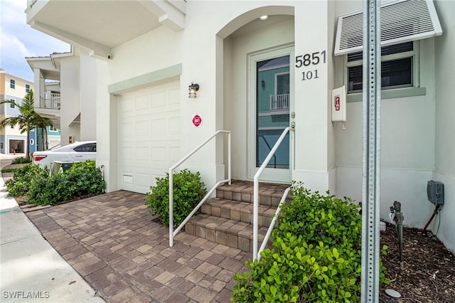 5851 Shell Cove Dr Unit 101A, Cape Coral, FL 33914 - view of exterior entry with a garage, stucco siding, and decorative driveway