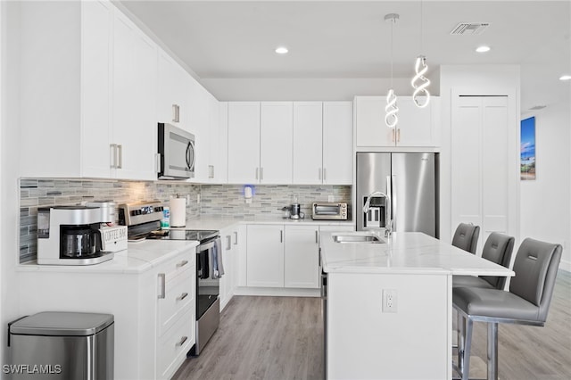 5851 Shell Cove Dr Unit 101A, Cape Coral, FL 33914 - kitchen featuring stainless steel appliances, light wood finished floors, a sink, a kitchen breakfast bar, and an island with sink