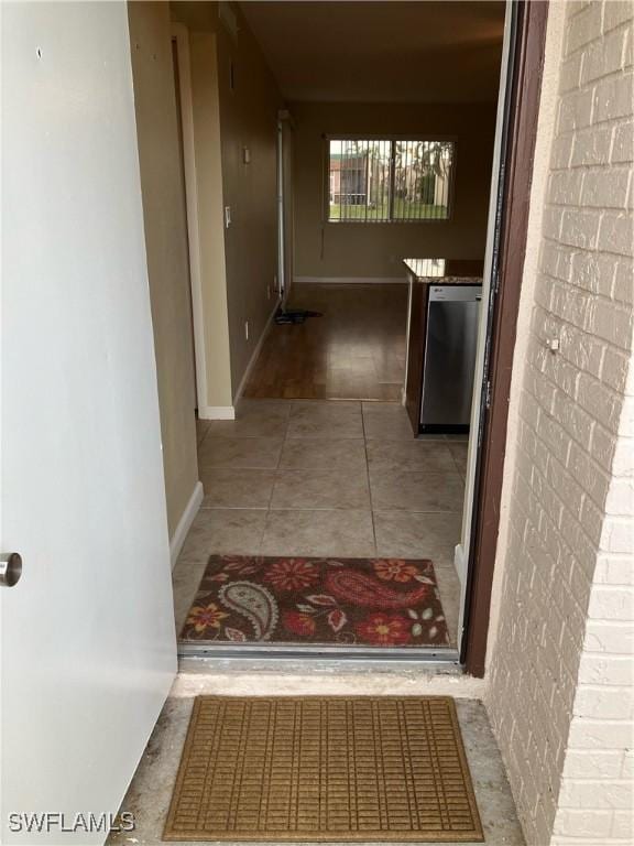 corridor featuring tile patterned flooring and brick wall