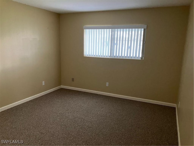 unfurnished room with dark carpet and baseboards