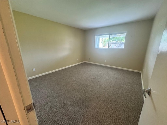 carpeted empty room featuring baseboards