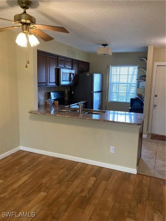 6300 S Pointe Blvd Unit 316, Fort Myers, FL 33919 - kitchen with stainless steel appliances, a peninsula, light wood-style floors, light stone countertops, and ceiling fan