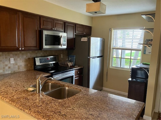 6300 S Pointe Blvd Unit 316, Fort Myers, FL 33919 - kitchen featuring appliances with stainless steel finishes, a sink, backsplash, baseboards, and light stone countertops