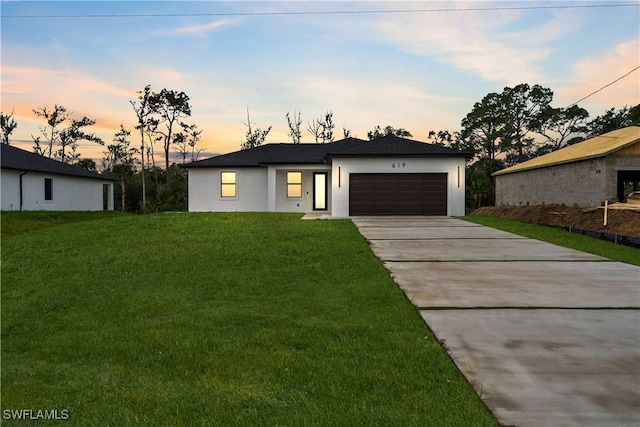 619 Greenbriar Blvd, Lehigh Acres, FL 33972 - view of front of house featuring concrete driveway, an attached garage, stucco siding, and a front lawn