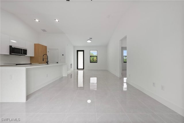 619 Greenbriar Blvd, Lehigh Acres, FL 33972 - unfurnished living room featuring a sink, light tile patterned floors, baseboards, and high vaulted ceiling