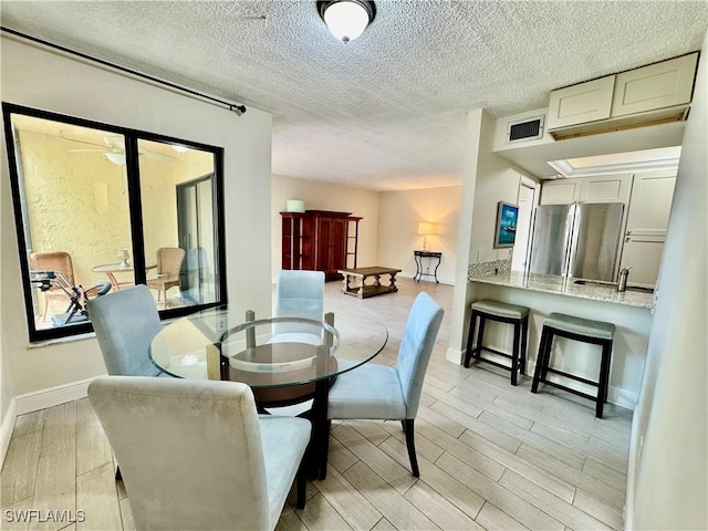3625 Boca Ciega Dr Unit 110, Naples, FL 34112 - dining space featuring light wood-style flooring, baseboards, and a textured ceiling