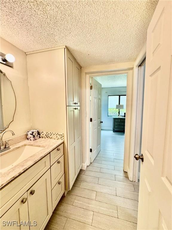 3625 Boca Ciega Dr Unit 110, Naples, FL 34112 - bathroom with vanity, a textured ceiling, and wood tiled floors