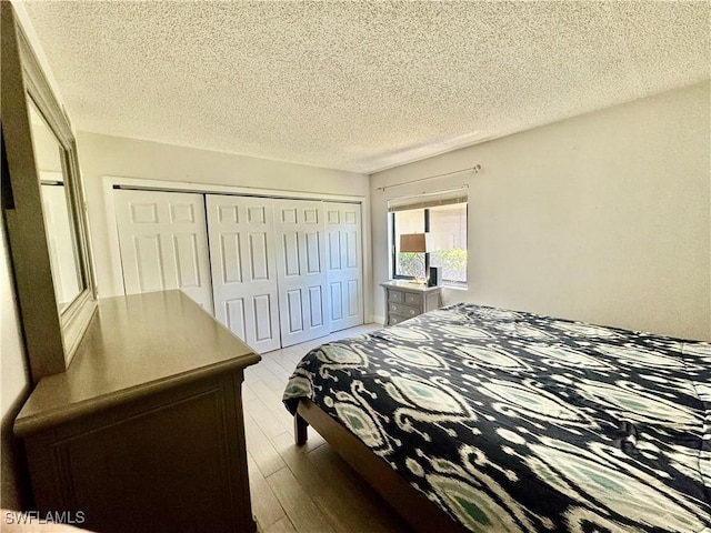 3625 Boca Ciega Dr Unit 110, Naples, FL 34112 - bedroom with light wood-type flooring, a textured ceiling, and a closet