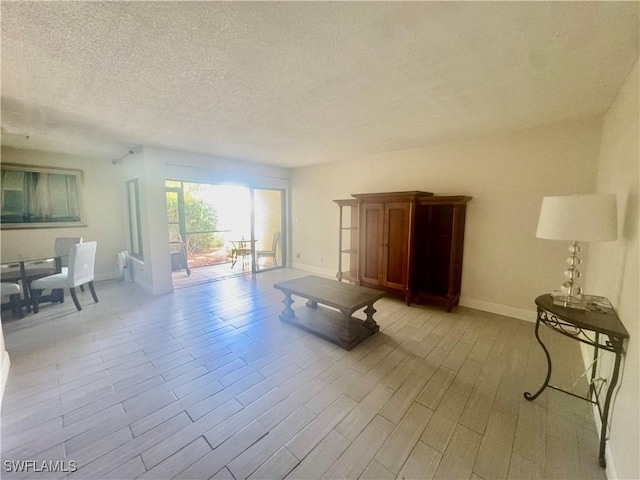 3625 Boca Ciega Dr Unit 110, Naples, FL 34112 - living room featuring a textured ceiling, baseboards, and wood finished floors