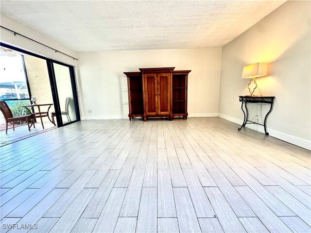 3625 Boca Ciega Dr Unit 110, Naples, FL 34112 - unfurnished living room with a textured ceiling, light wood-type flooring, and baseboards