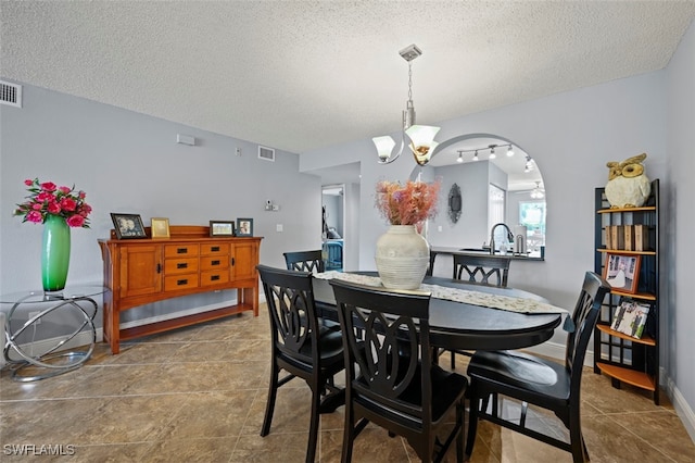 1210 Yesica Ann Cir Unit C105, Naples, FL 34110 - dining space with a textured ceiling, a chandelier, arched walkways, and tile patterned floors