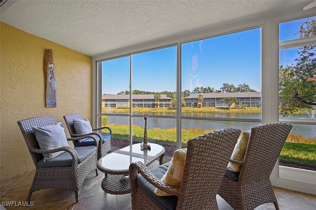 1210 Yesica Ann Cir Unit C105, Naples, FL 34110 - sunroom featuring a textured wall, a water view, a textured ceiling, expansive windows, and tile patterned floors