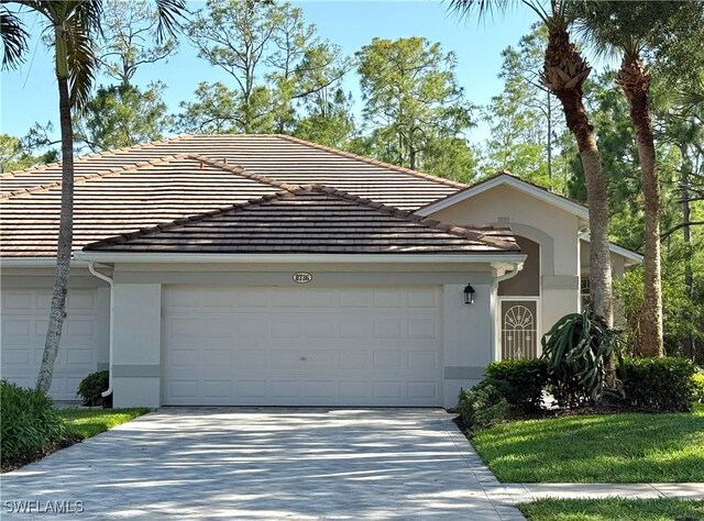 8736 Naples Heritage Dr, Naples, FL 34112 - view of front of property featuring stucco siding, driveway, and a garage