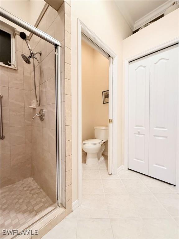 8736 Naples Heritage Dr, Naples, FL 34112 - bathroom with a stall shower, tile patterned flooring, toilet, and crown molding