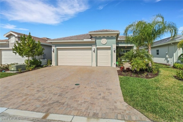 16712 Gilroy St, Bonita Springs, FL 34135 - mediterranean / spanish house with stucco siding, decorative driveway, an attached garage, a front yard, and cooling unit